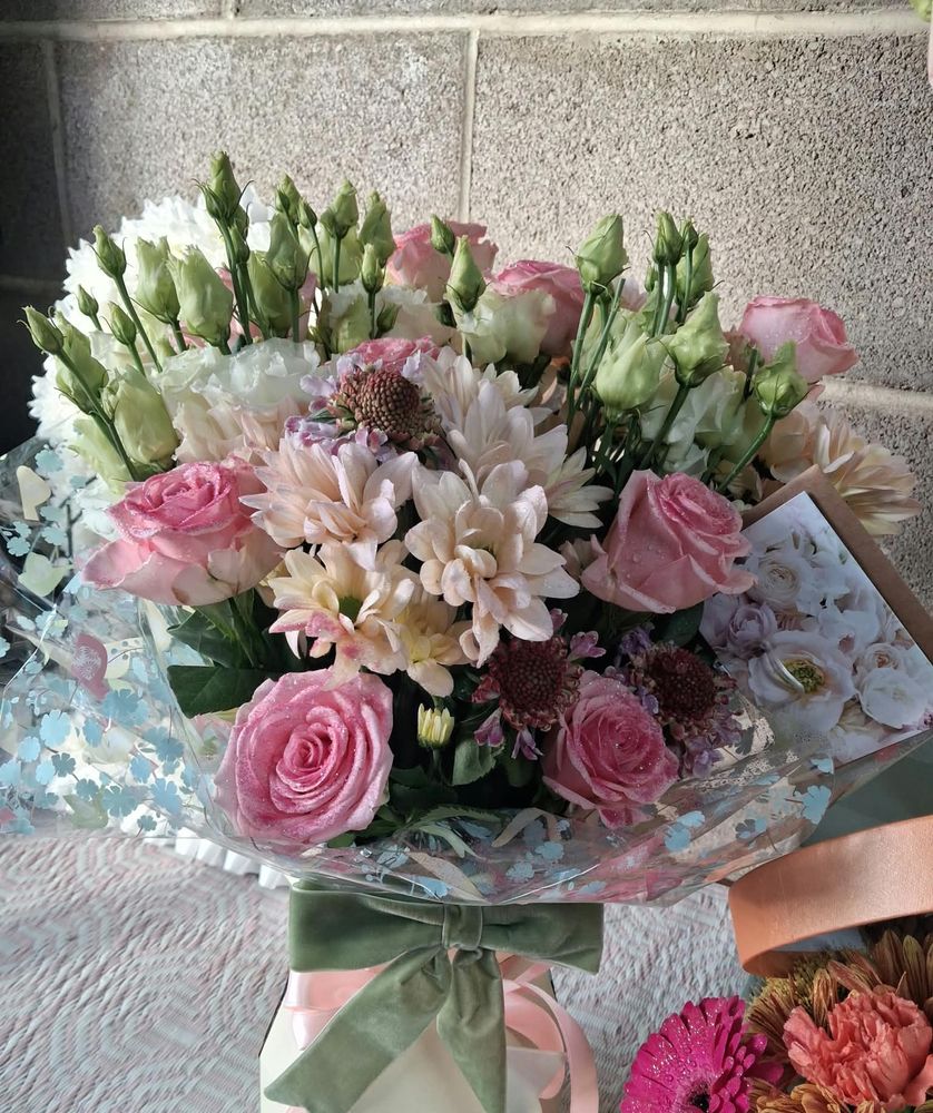 A pink rose and lisianthus bouquet in a gift box with a sage velvet bow