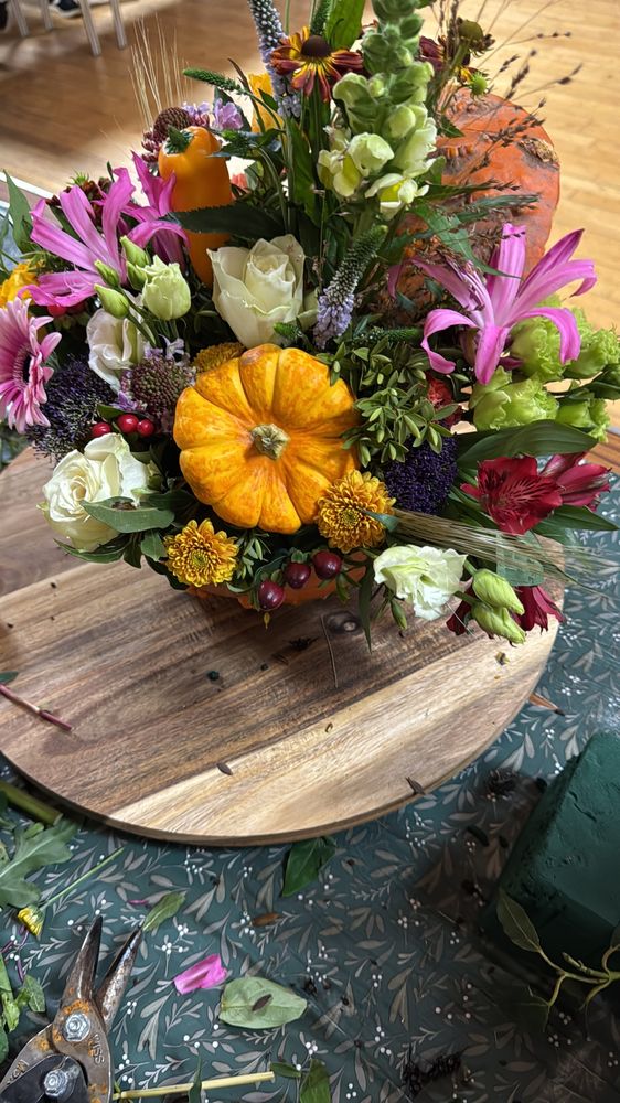 A finished pumpkin arrangement with roses, lilies, chrysanthemums and a mini pumpkin