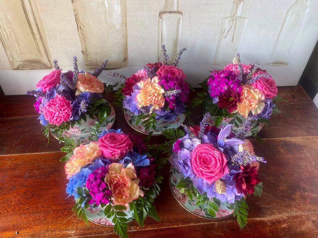 Five finished teacup arrangements in pinks, purples and corals